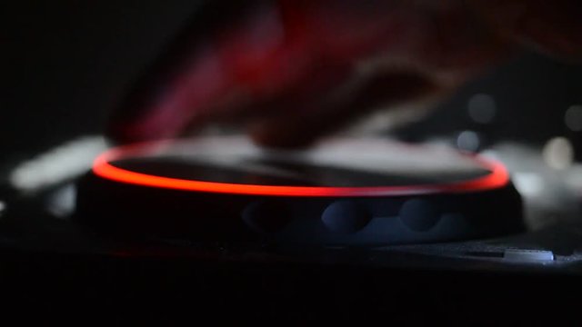 DJ Spinning, Mixing, and Scratching in a Night Club, Hands of dj tweak various track controls on dj's deck, strobe lights and fog, selective focus, close up. Dj Music club life concept