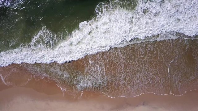 Aerial view of ocean waves crashing on beach, 4K drone footage.