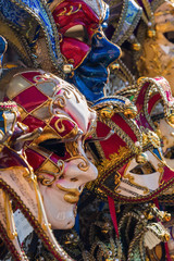 Fototapeta na wymiar bulk of Venetian masks hanging at a rack