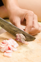 Chef slice streaky pork on wooden board for cooking