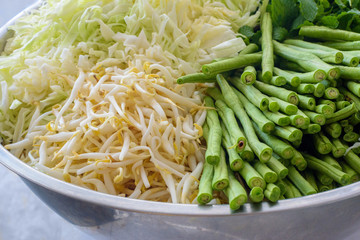 Peppermint, green beans, bean sprouts and cabbage lay in same bowl prepare for fish curry sauce