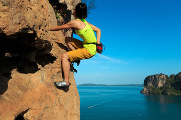 free solo woman rock climber climbing at seaside cliff