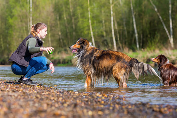 young woman with two dogs at the river
