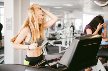 young woman is engaged fitness in gym. Performs cardio load on treadmill, running and walking with acceleration. sport, fit, lifestyle, technology and people concept