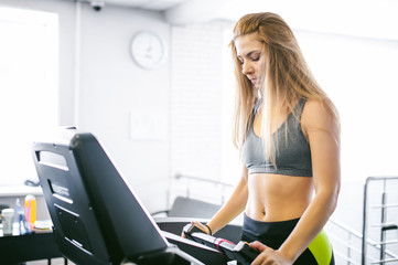 Fototapeta na wymiar young woman is engaged fitness in gym. Performs cardio load on treadmill, running and walking with acceleration. sport, fit, lifestyle, technology and people concept