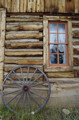 Fototapeta na wymiar Old west cabin window and wagon wheel
