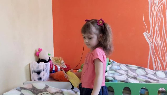 A little girl is playing with a doll in her room