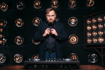 Professional bearded disk jockey at the console in studio ready to start music party. Nightclub, dance, famous rhythms, console.