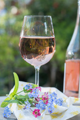 Glas of cold rose wine, outdoor terrase, sunny day, spring garden flowers