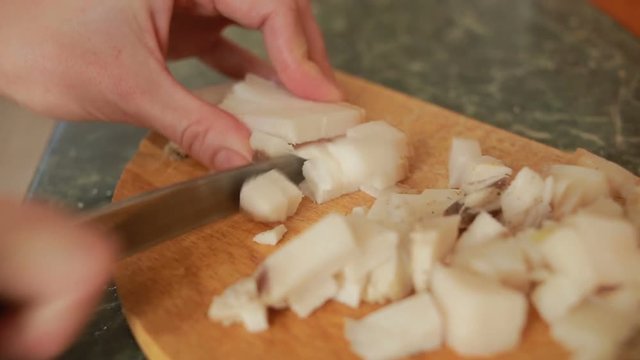 Cutting pork fat with a knife on a cutting board