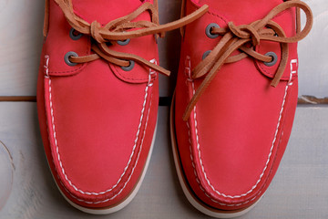 Red boat shoes on wooden background. Top view. Close up.