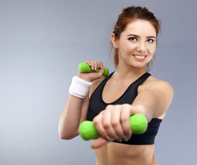  Young smiling attractive  woman  with green dumbbells in hands