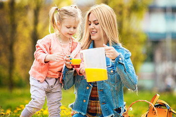 Mother and Daughter Drinking Orange Juice in Park