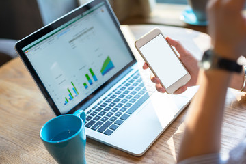 Businesswoman using smart phone and laptop.