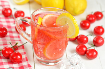 Fruit cherry ice tea with slice of lemon in mug and cherries