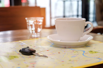 Coffee and car key place on the map with glass water.