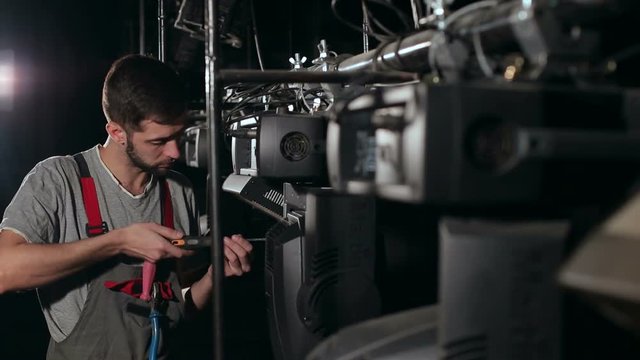 The lighting engineer repairs the light device on stage