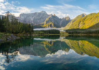 Beautiful, sunny and foggy morning on the alpine lake in the julian alps in italy