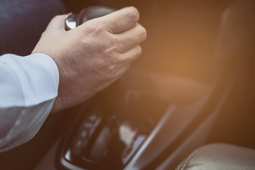 Man driving car while holding automatic gear shift control