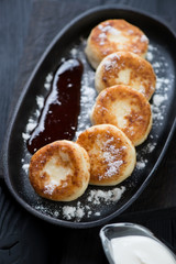 Closeup of curd pancakes or syrniki with powdered sugar served in a frying pan