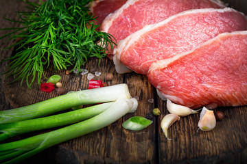 Raw meat steak with spices on a wooden board, selective focus