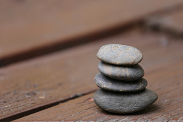 Balance Stones stacked to pyramid on brown wood background.