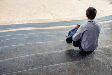 Handsome young businessman sitting on the stairs and using his smartphone (selective focus).