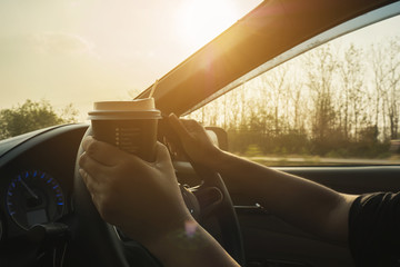 Fototapeta premium Lady driving car while holding a cup of coffee