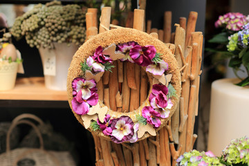 Stroik, dekoracja ze sztucznych kwiatów na krążku z trzciny.