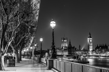 Black and white artistic night photo of London Eye, Big Ben and Houses of parliament in London, UK.