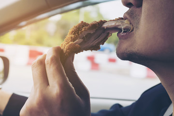 Business man driving car while eating fried chicken dangerously