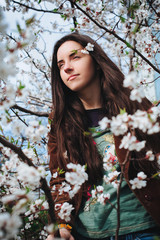 Young pretty long-haired girl among the flowering branches.