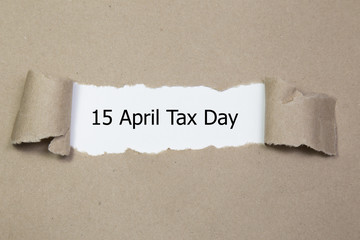 The word 15 april tax day appearing behind torn paper. 