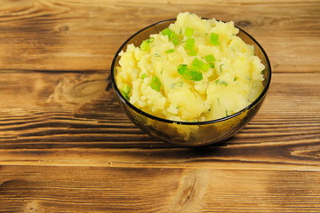 Mashed potatoes in glass bowl on wooden table