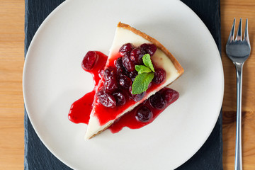 Cheesecake on plate with cherry sauce, top view