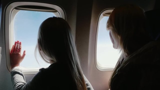 Mom and daughter in the airplane. We travel together, we look in the porthole