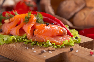 Slices of smoked salmon with dill, chili pepper, tomatoes and bread