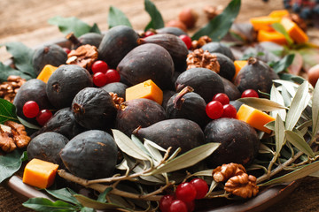 Figs with cheese and viburnum mix closeup. Delicious snack for wine of fig fruits with red berries and cheese slices. Gourmet, delicatessen, appetizer concept
