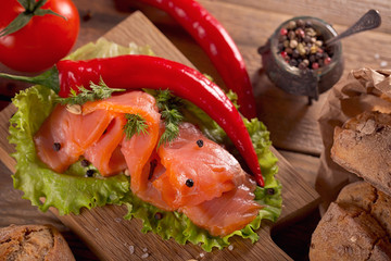 Slices of smoked salmon with dill, chili pepper, tomatoes and bread