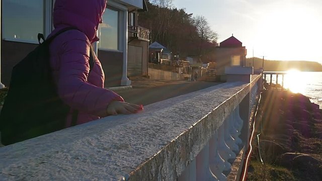 A beautiful young girl walks, touches stone parapet to sea. Pink clothes, spring time, Slow motion. Close-up shot
