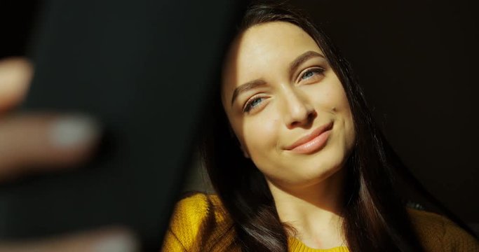 Portrait of beautiful smiling woman taking selfie indoor. Pretty young woman taking photos of herself at home. Smiling to the camera. Close up shot