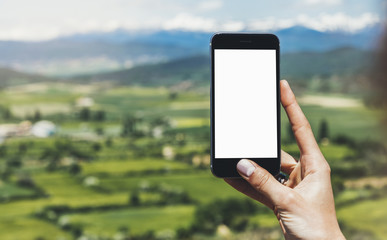 Hipster photograph on smart phone gadget mobile, mock up of blank screen. Traveler hold and using in hand mobile on background mountain landscape horizon. Tourist look map on trip, lifestyle concept