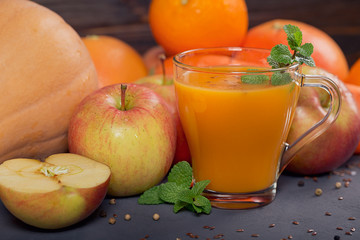 Fresh carrot, apple, pumpkin, orange, grapefruit on dark table.