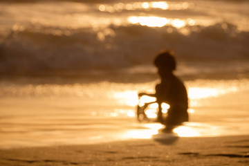 Fototapeta na wymiar Blur kid playing sand on the beach during sunset abstract background.