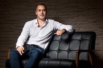 Fototapeta premium Young handsome businessman sitting with confidence on leather couch thinking