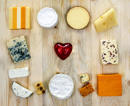 Love of cheese - variety of cheeses with heart, on wooden background.