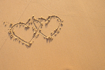 Two hearts drawn in the sand at the beach.