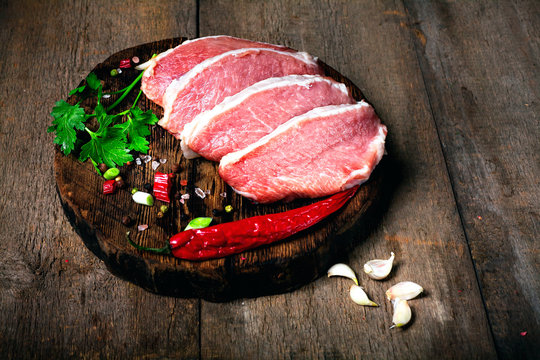 Raw juicy meat steaks ready for roasting on a black chalk board background. Space for text