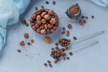 Hazelnut, coffee beans and cocoa powder in light blue background.