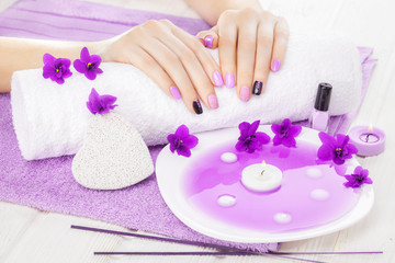 Obraz na płótnie Canvas beautiful purple manicure with violet, candle and towel on the white wooden table.